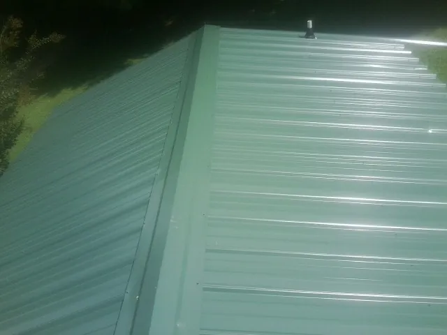 New green metal panels meeting at the ridge of a roof — Flat Roof Repair work by our crew in Eldon