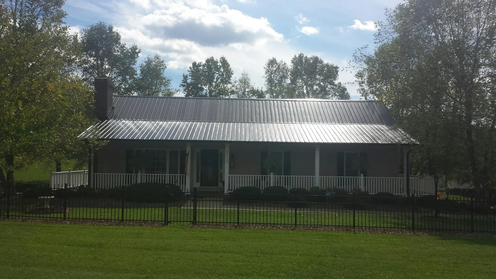 Gray metal roof on a brick ranch with a full width front porch — Gutter Guard Installation work by our crew in Eldon