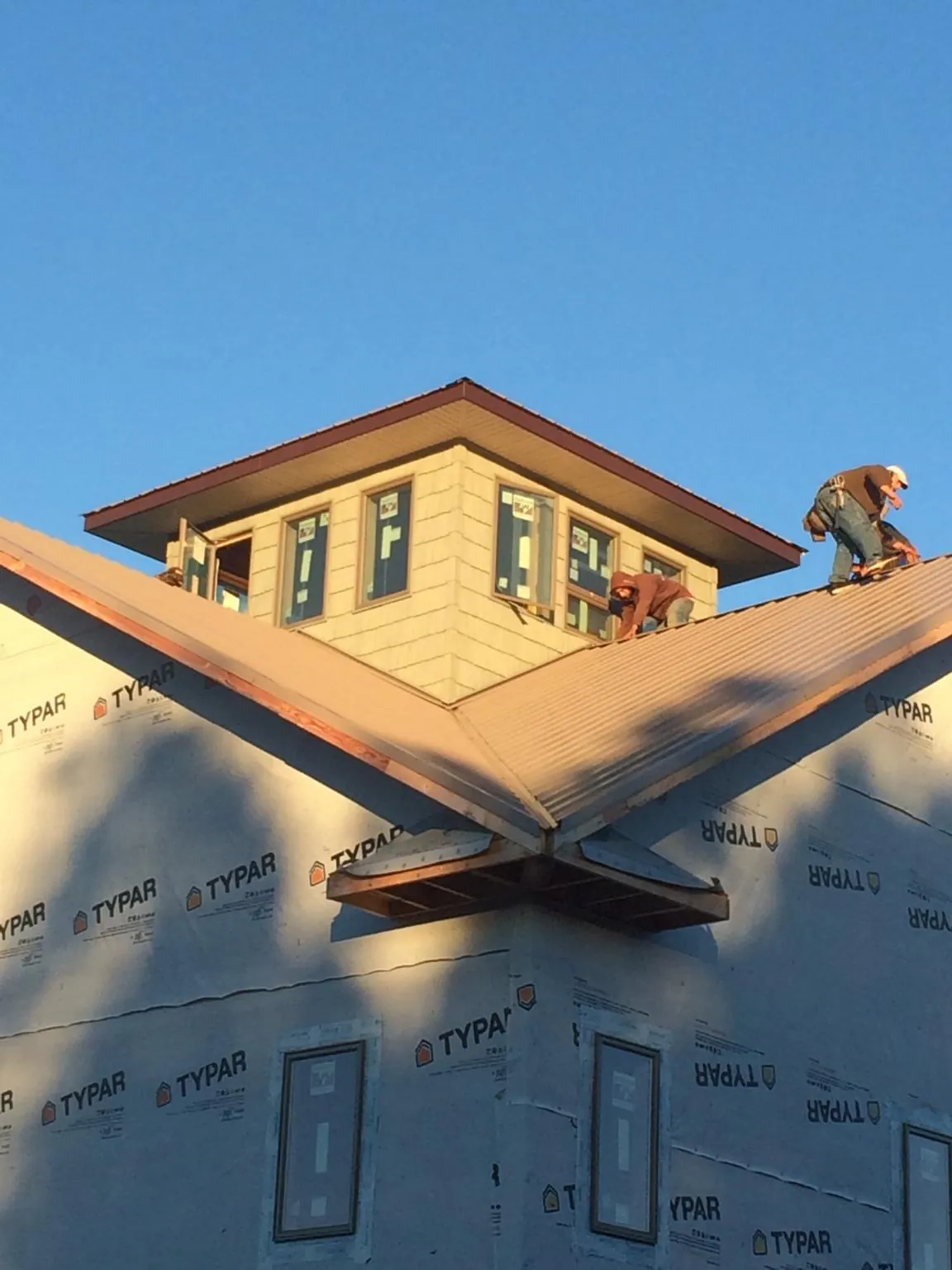 Roofers working around a rooftop cupola on a new metal roof at sunset — Roof Waterproofing in Eldon by Roofing Brothers